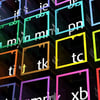 Des cubes transparents aux bordures colorées affichent des combinaisons de lettres blanches en perspective sur un fond sombre.