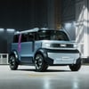 A futuristic compact electric SUV labeled "Hipster Concept" is parked inside a spacious, well-lit industrial warehouse.